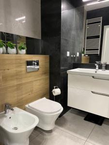 a bathroom with a white toilet and a sink at Racławickie 28A in Lublin +8 photos