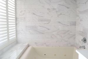 een wit bad in een badkamer met marmeren muren bij Days Inn by Wyndham Near City Of Hope in Duarte