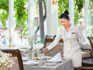 a woman is setting a table in a restaurant at Furama Resort Danang in Da Nang