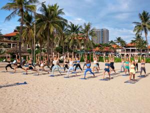 a group of people doing yoga on the beach at Furama Resort Danang in Danang
