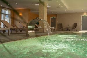 a swimming pool with a fountain in a hotel room at AM HOTEL WELLNESS **** in Rimavská Sobota