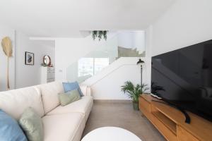 a living room with a white couch and a large tv at White Medano apartment. New with fast Wifi in El Médano