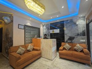 un vestíbulo con dos sofás marrones y un hombre parado en un mostrador en Hotel Singh International, Amritsar, en Amritsar