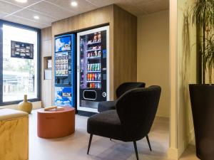 a room with two chairs and a soda machine at Hotel ibis budget Chatillon Paris Ouest in Châtillon