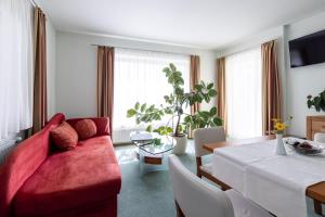 a living room with a red couch and a table at Pension Klug Adults only - DorfResort Mitterbach in Mitterbach