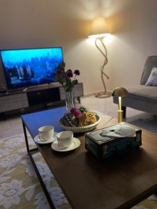 a living room with a table with two cups and a television at شقة فندقية عوائل ثلاث غرف نوم وغرفة معيشة ومطبخ ومدخل خاص in Riyadh Al Khabra