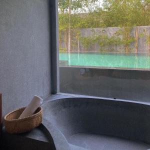 a bath tub next to a window with a view of a pool at Palm View Villa in Hoi An