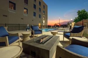 un patio con chimenea, sillas y piscina en Hawthorn Extended Stay by Wyndham Pflugerville, en Pflugerville