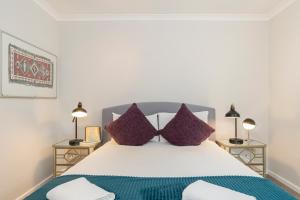 um quarto com uma cama grande e almofadas roxas em Goodge Apartments em Londres