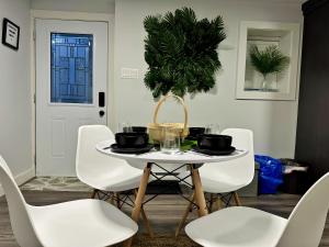 a white dining room with a table and white chairs at Palm Suite St Johns - Luxury One Bedroom Apartment in St. John's