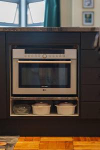 a microwave oven in a black cabinet with bowls at Loft Apt in City Centre Iconic Art Deco Building in Cape Town