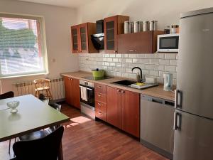 a kitchen with wooden cabinets and a table and a refrigerator at Kosice in Košice