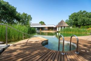 um calçadão de madeira que leva a um lago com uma casa em Vila Vita Pannonia em Pamhagen