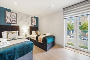 a bedroom with two beds and a window at Cosy London Retreat - Sleeps 6 in London