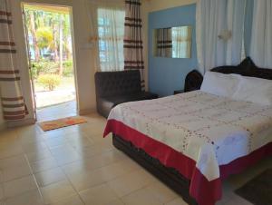 a bedroom with a bed and a chair and a window at BIMOSS BEACH RESORT in Mbita