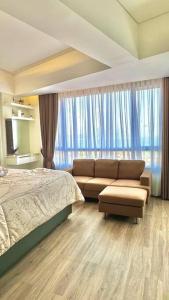 a bedroom with a bed and a couch and a window at The Bay Apartemen Deluxe Lampung City Mall in Kuala