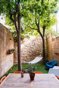 a wooden table with a hammock in a yard with trees at Luxurious eclectic home in a traditional village in Tarxien
