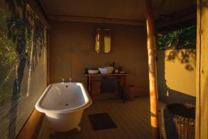 a bathroom with a bath tub and a sink at Cha Cha Metsi in Maun