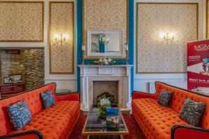 a room with two orange couches and a fireplace at Muthu Westcliff Hotel (Near London Southend Airport) in Southend-on-Sea