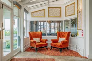 twee oranje stoelen in een hal met ramen bij Muthu Westcliff Hotel (Near London Southend Airport) in Southend-on-Sea