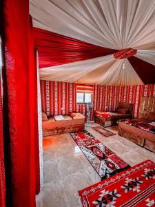 a living room with red curtains and couches and rugs at RUM EiLEEN LUXURY CAMP in Wadi Rum