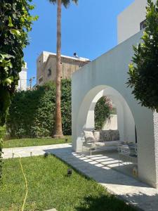 Villa de maitre magnifique, spacieuse avec jardin في المرسى: كنب جالس تحت قوس في ساحة