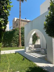 a couch sitting under an arch in a yard at Villa de maitre magnifique, spacieuse avec jardin in La Marsa