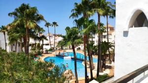 a resort pool with palm trees and people in it at Beautiful 1 bedroom apartment in Roquetas de Mar