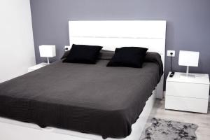 a bedroom with a large black bed with two lamps at Apartamento primera línea mar Garachico in Garachico
