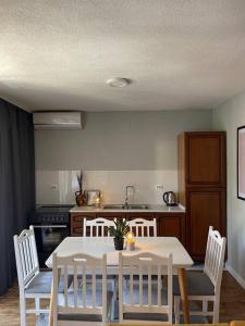 uma cozinha com uma mesa branca e cadeiras brancas em Etern Stays - Nook Apartment em Pristina