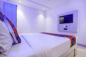 a white room with a bed and a tv at FabExpress Embassy Suites in Mumbai