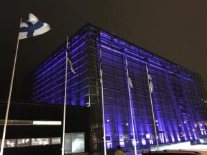 a blue building with flags in front of it at Ilmastoitu 55 m2 huoneisto saunalla Lahden satamassa in Lahti