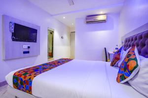 ein Schlafzimmer mit einem großen weißen Bett und einem TV in der Unterkunft FabExpress Embassy Suites in Mumbai
