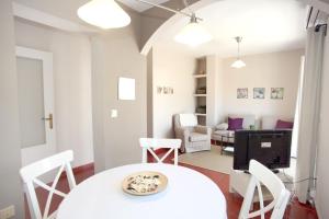 une salle à manger avec une table et des chaises blanches dans l'établissement Sleepin Sevilla Catedral, à Séville