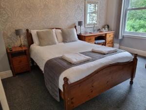 Fellview Guest House في باونيس أون وينديرمير: غرفة نوم مع سرير مع وسادتين ومكتب