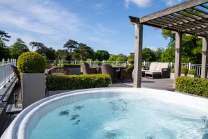 a hot tub on a deck with a pergola at Chewton Glen Hotel - an Iconic Luxury Hotel in New Milton