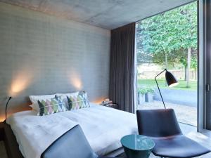 een slaapkamer met een bed, een stoel en een raam bij Notarishuys "Pure Hotel" in Diksmuide