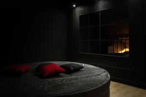 a black room with a bed with two red pillows at LA PERLE NOIRE in Agde