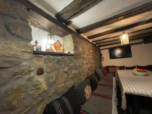 a restaurant with a stone wall and a table and chairs at Guest House “Anchetata” in Apriltsi