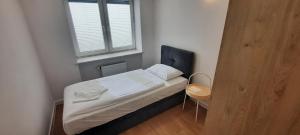 a small bedroom with a bed and a window at Apartamenty Sportowe AWF in Katowice