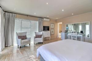 a bedroom with a large white bed and two chairs at Thyme Wellness Spa and Guesthouse in Cape Town