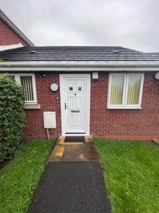 a red brick house with a white door at Pinfold Court Apartments in Knowsley