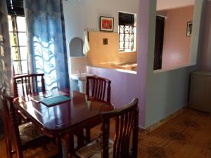 a dining room with a table and chairs and a sink at COZYCRIB in Fort Portal