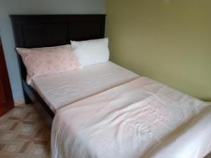 a bed with white sheets and a pillow at COZYCRIB in Fort Portal