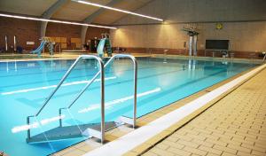 a large swimming pool with blue water in a gym at Helle Aktivitetshotel in Årre