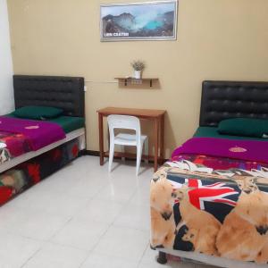 a bedroom with two beds and a table and a chair at Dannu's Homestay Ijen and Bromo Tour in Banyuwangi