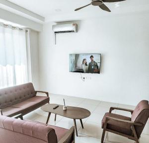 a living room with a couch and a tv on the wall at There's no place like home! By Mizu Homestay. in Miri