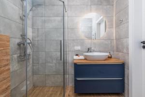 a bathroom with a sink and a glass shower at Apartments with Parking - Klimaty Baltyku by Renters in Dziwnów