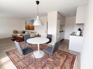 a kitchen and living room with a white table and chairs at Moderne & helle Wohnung mit Netflix & Bergsicht in Wetzikon