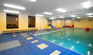 een zwembad met blauwe en gele tegelvloeren en een zwembad bij Hotel Deichkrone - Familotel Nordsee in Norddeich